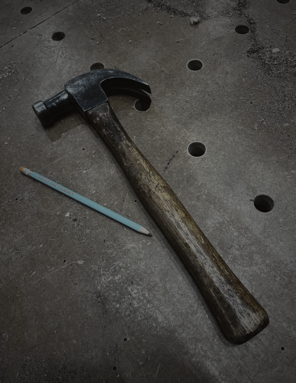 A forged hammer and pencil resting on a workshop bench
